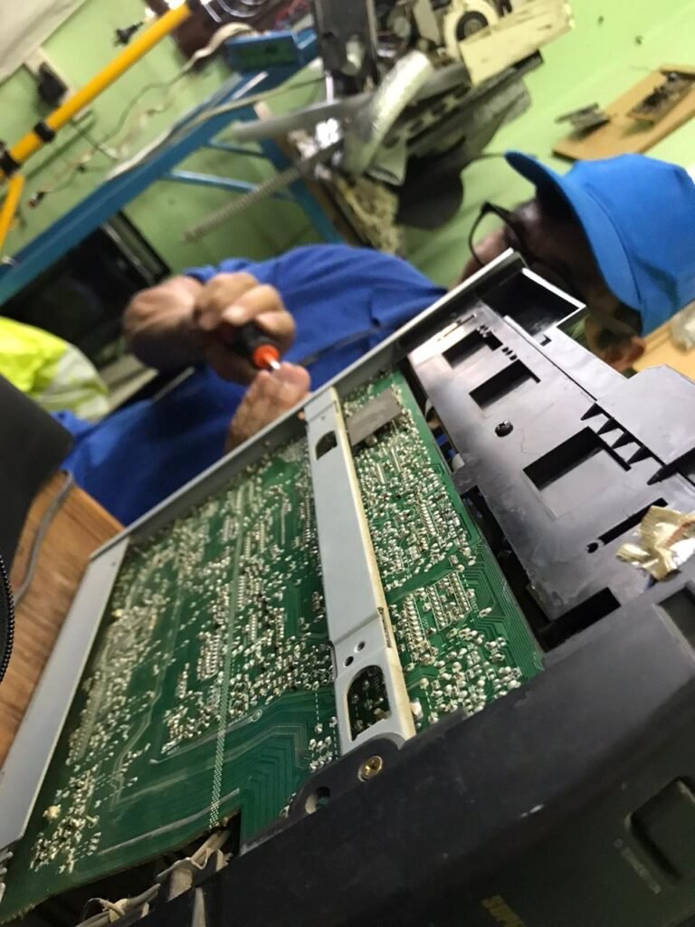 Alumno con gorra azul trabajando con herramientas de precisión sobre el circuito impreso y las soldaduras de una placa electrónica de un artefacto del hogar