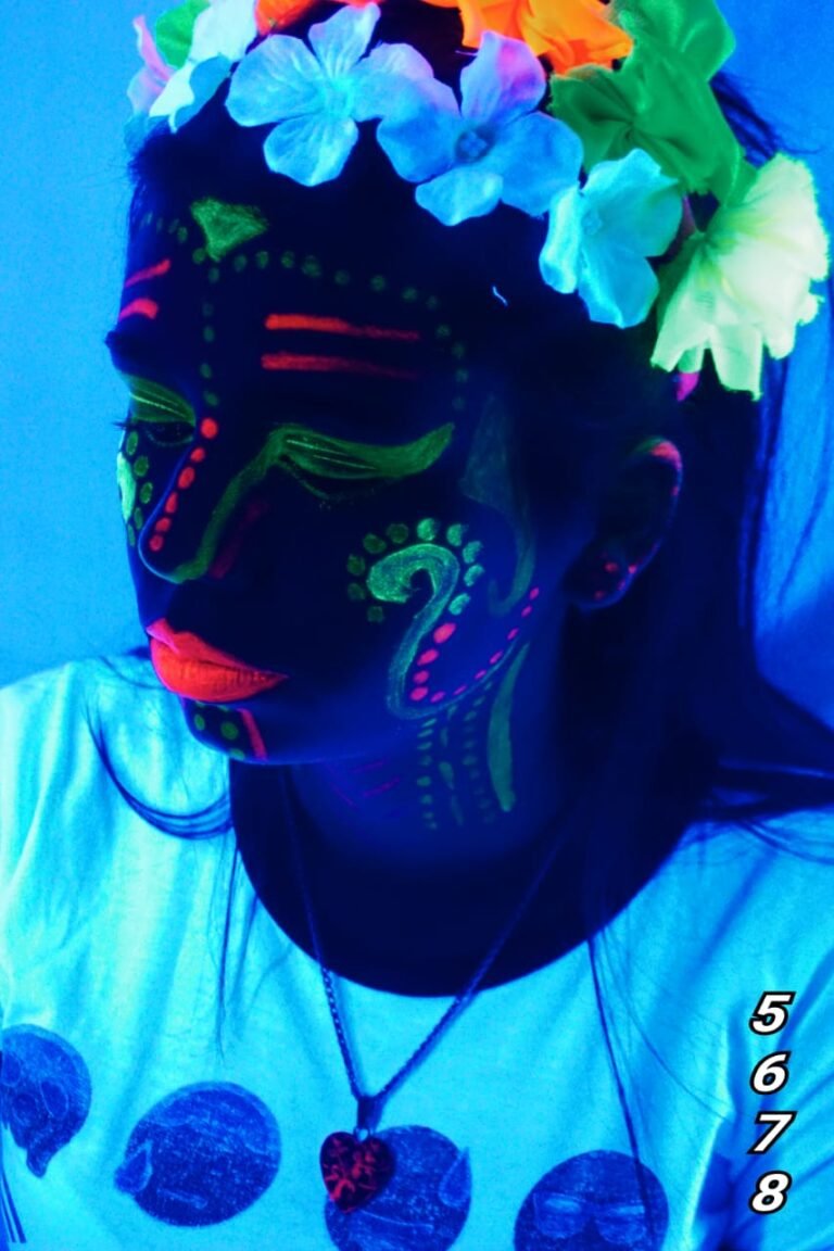 Primer plano de un retrato fotográfico artístico a una joven con maquillaje de neón fluorescente y corona de flores bajo efectos de luz negra ultravioleta